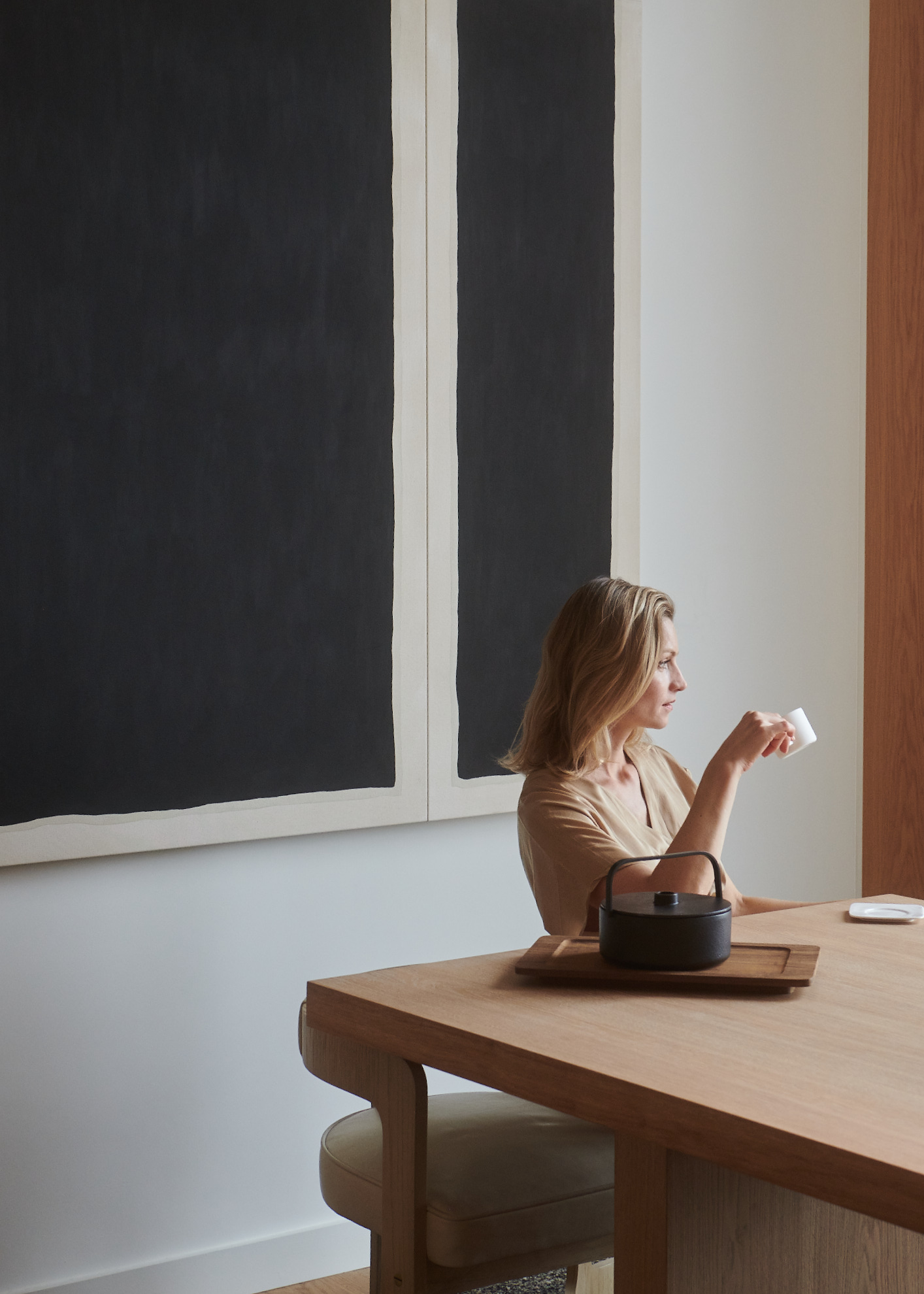 Anna Yermakova seated beside a teapot and large monochrome artworks