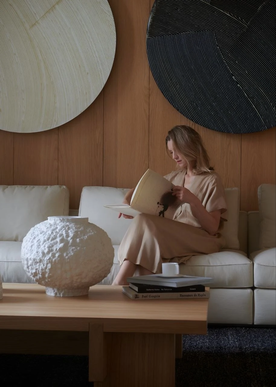 Anna Yermakova in a calm interior with sculptural art and warm brown backdrop